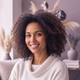 Headshot of a smiling woman with dark, curly hair, exuding happiness and confidence.